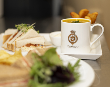 A plate with a sandwich, mug of soup and potato wedges, ready to be served in the Tearoom.