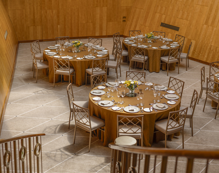 From the staircase, a view of Fingal Hotel's Ballroom. There are four tables set for dinner. The tables have gold table cloths.